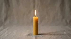 A lit pure beeswax taper candle burning with a bright, clean, soot-free flame against a neutral background.