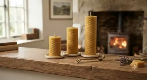 A set of three natural, sustainable British beeswax pillar candles displayed on a wooden mantlepiece.