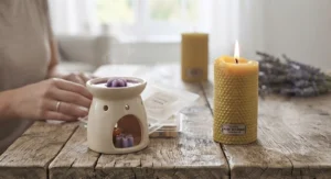 Lit beeswax pillar candle burning brightly next to a scented wax melt sample pack on a ceramic burner.